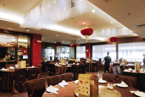 a restaurant with tables and chairs and a man standing in a room at Times Hotel Brunei in Bandar Seri Begawan