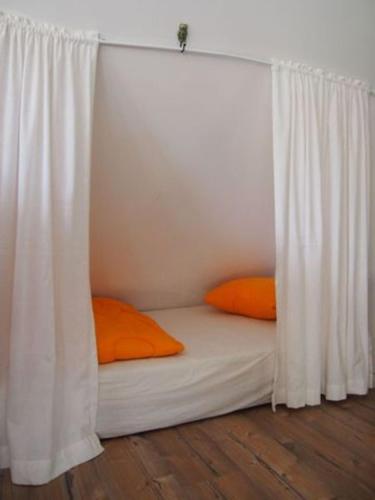 a white bed with orange pillows in a room at Reetdach - Promenadenblick - 500m zum Strand in Prerow