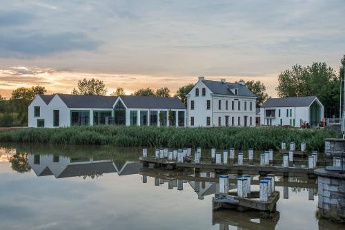 a group of white buildings next to a body of water at De Koolputten in Waasmunster