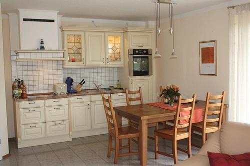 a kitchen with a wooden table and chairs in a kitchen at Landhaus Storchenblick - WE-20160 in Lonvitz