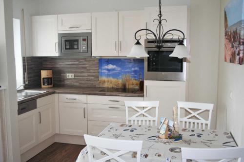 Una cocina con gabinetes blancos y una mesa y sillas. en Komfortferienwohnung Strandgut, en Sassnitz
