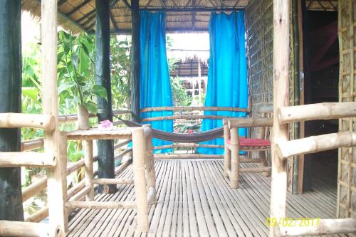 a porch of a house with a swing and blue curtains at Battambang Dream Bungalows in Battambang