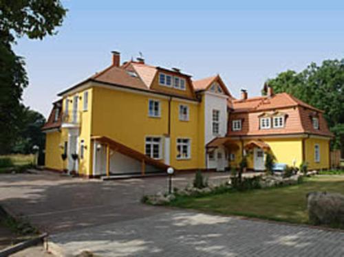 a large yellow house sitting on the side of a street at Herrenhaus Poppelvitz in Maltzien