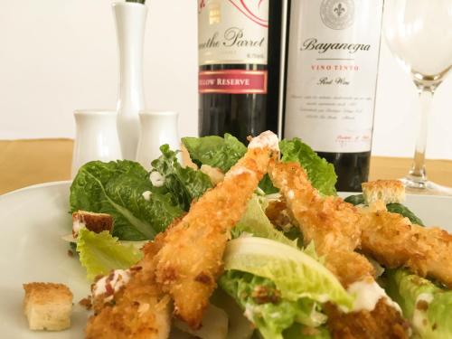 a plate of food with a salad and a bottle of wine at Tropical Breeze in Siem Reap