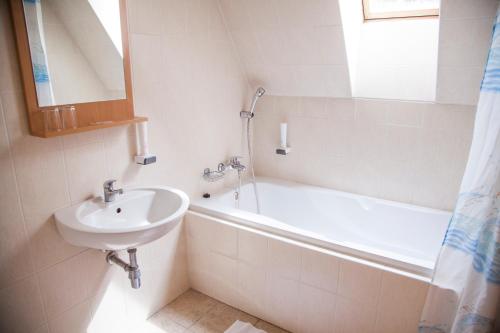 y baño blanco con lavabo y bañera. en Hotel Eminent, en Zlaté Moravce