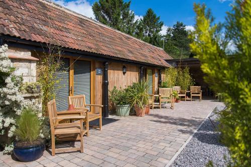a patio with wooden chairs and a building at Widbrook Barns in Bradford on Avon