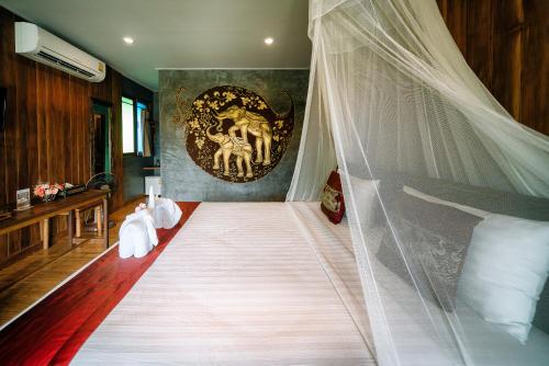 a large white bed sitting under a large window at Sawasdee Sukhothai Resort in Sukhothai