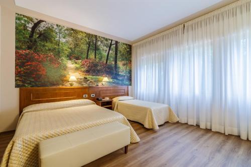 two beds in a room with a painting on the wall at Hotel Villa Delle Rose in Pescia