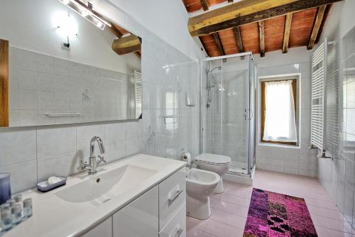 a white bathroom with a sink and a toilet at Villa Morandi by PosarelliVillas in Loro Ciuffenna