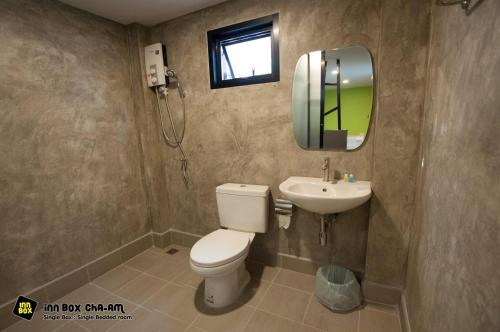 bagno con servizi igienici, lavandino e specchio di Inn Box ChA-AM a Petchaburi