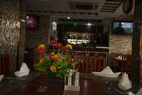 a restaurant with a table with a vase of flowers at Zimbo Golden Hotel in Dar es Salaam