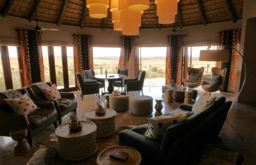 a living room with couches and a table and windows at Nambiti Plains Lodge in Nambiti Private Game Reserve