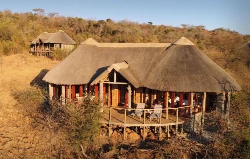 a hut with a thatched roof in a field at Nambiti Plains in Nambiti Private Game Reserve