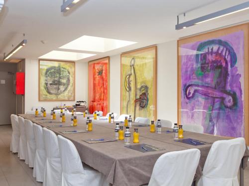 a long table in a room with white chairs and paintings at Hotel Sagrada Familia in Barcelona