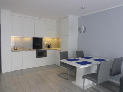 ポゴジェリツァにあるMorski22の白いキャビネット、テーブルと椅子付きのキッチンが備わります。