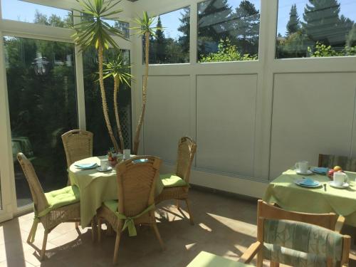 een eetkamer met een tafel, stoelen en ramen bij Panorama Hotel Pension Frohnau in Bad Sachsa