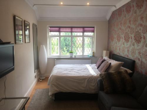 a bedroom with a bed and a window and a couch at Albemarle Apartment in Bromley