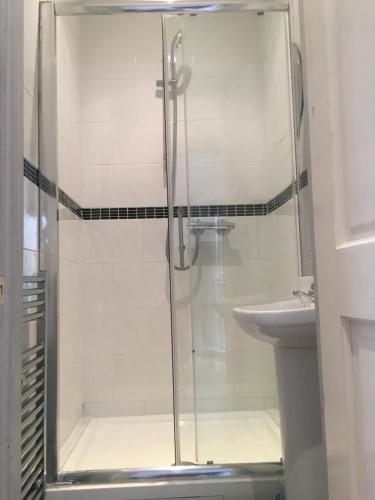a shower with a glass door next to a sink at Albemarle Apartment in Bromley