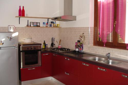 a kitchen with red cabinets and a white refrigerator at Casa la Pineta in Pieve a Scuola