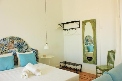 a bedroom with a bed with a mirror and a chair at Alojamentos Vista Mar-Luisa Todi in Setúbal