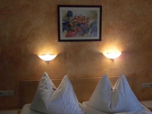 two pillows on a bed with two lights on the wall at Gästehaus Hartweger in Haus im Ennstal