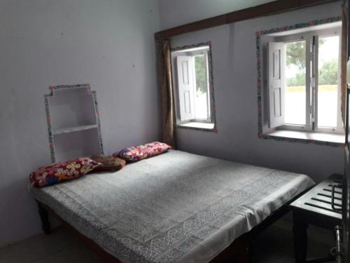 a bed in a room with two windows at Hotel Paramount Palace in Pushkar