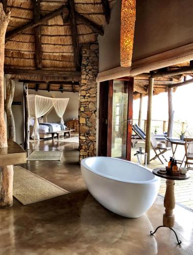 a large white bath tub in a room with a bedroom at Nambiti Plains Lodge in Nambiti Private Game Reserve