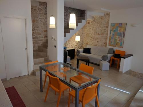 ein Wohnzimmer mit einem Glastisch und orangenen Stühlen in der Unterkunft Lovely Stone House Conversano Puglia in Conversano