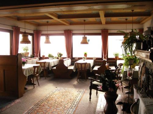 un restaurante con mesas, sillas y ventanas grandes en Gästehaus Katharina, en Kiefersfelden