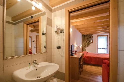 a bathroom with a sink and a bedroom with a bed at Albergo al Fontanin in Rabbi