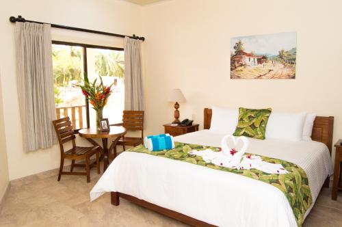 um quarto com 2 camas, uma mesa e uma janela em La Foresta Nature Resort em Quepos