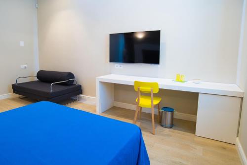 Rossano StazioneにあるB & B REGINA MARGHERITAのデスク、テレビ、黄色い椅子が備わる客室です。