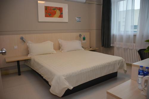 a bedroom with a bed with white sheets and pillows at JinJiang Inn Tianjin Steel Tube Company in Tianjin