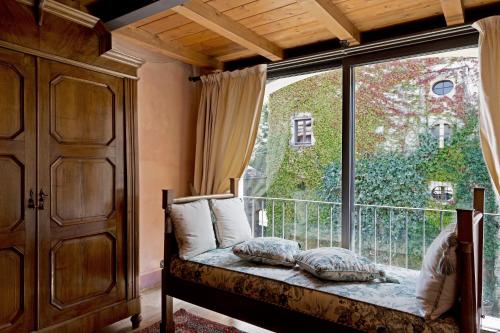 a bedroom with a large window with a bed and pillows at Hotel Locanda Dei Mai Intees in Azzate