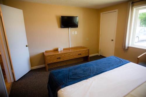 a bedroom with a bed and a tv on the wall at Steelhead Inn in Erie