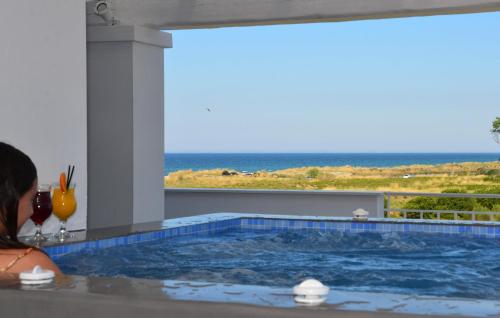 a woman sitting in a hot tub with a view of the ocean at Hotel Evilion Sea And Sun in Nei Poroi