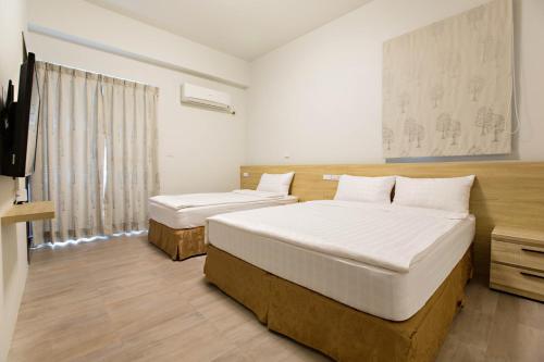1 dormitorio con 2 camas y TV. en Success 66 B&B en Taitung
