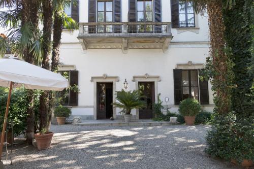 a white house with a balcony and palm trees at Hotel Locanda Dei Mai Intees in Azzate