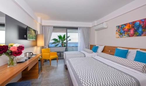 a hotel room with a bed and a desk with flowers at Floria Beach Hotel in Alanya