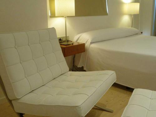 una habitación de hotel con una silla blanca y una cama en Hotel El Patiaz de la Reina Rana en Tauste