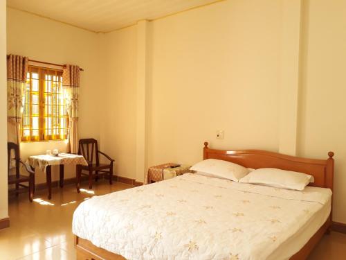 a bedroom with a bed and a table and a window at Ngoc Sang Guesthouse in Mui Ne
