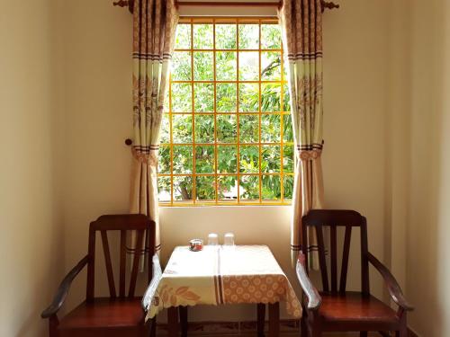 a table and two chairs in front of a window at Ngoc Sang Guesthouse in Mui Ne