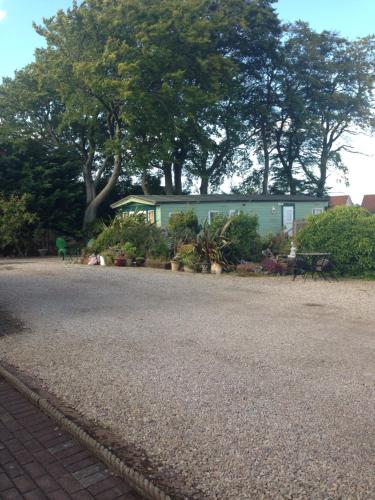 a green building with trees in the background at Rooms at Tarrareoch in Bathgate