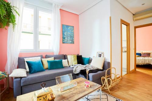 ein Wohnzimmer mit einem blauen Sofa und rosafarbenen Wänden in der Unterkunft Royal Palace Boutique in Madrid