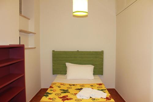 ローマにあるA Casa Di Magda (Al centro di Roma)のベッド1台(緑のヘッドボード、タオル2枚付)が備わる小さな客室です。