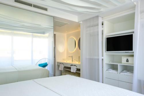 a hotel room with two beds and a television at Apartamentos Portu Saler in Es Pujols