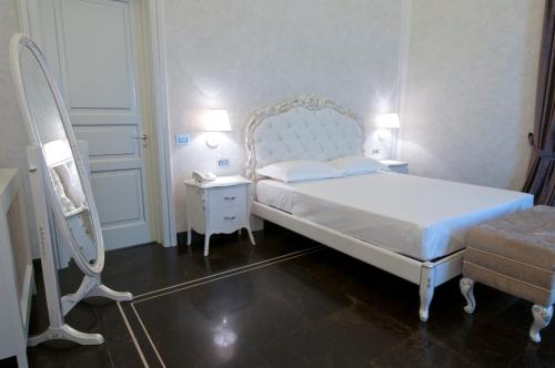 a bedroom with a white bed and a mirror at Palazzo Favacchio - Patanè in Scicli