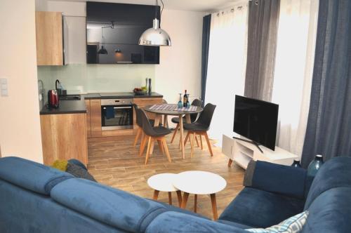 Il comprend un salon avec un canapé bleu et une cuisine. dans l'établissement Windrose Apartment, à Świnoujście