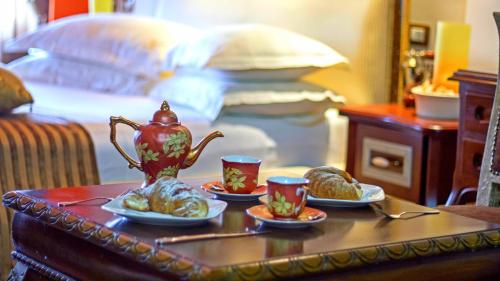 a tea set on a table with two cups and croissants at Hotel Boutique Vila Fernando Tirana in Tirana