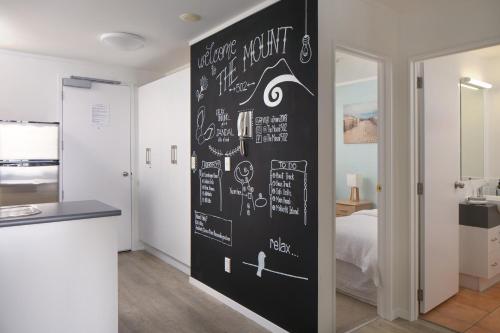 a room with a black wall with drawings on it at Ocean View Beach Escape - Top Floor Apartment, Mt Maunganui Base in Mount Maunganui
